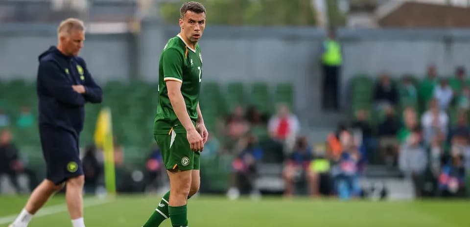 Player in green jersey during match with coach nearby