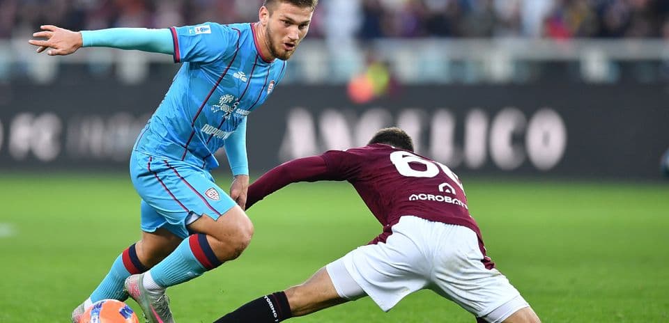 Cagliari player evading a tackle from Torino