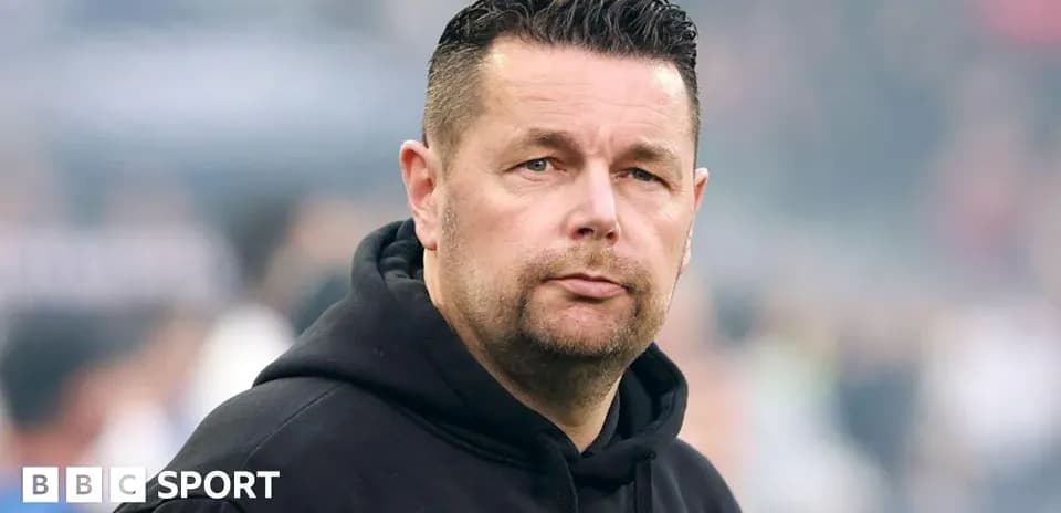 Man wearing a black hoodie on the sidelines