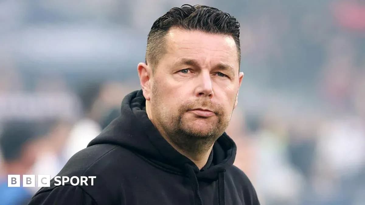 Man wearing a black hoodie on the sidelines