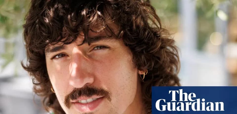 Man with curly hair and mustache smiling