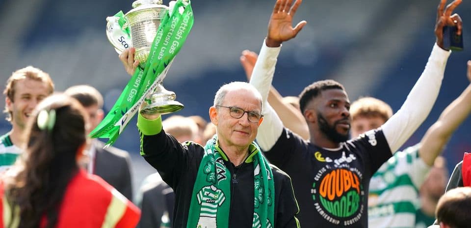 Man holding trophy with team celebrating in background