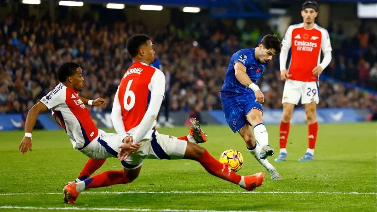 Chelsea player shooting while Arsenal defenders attempt to block