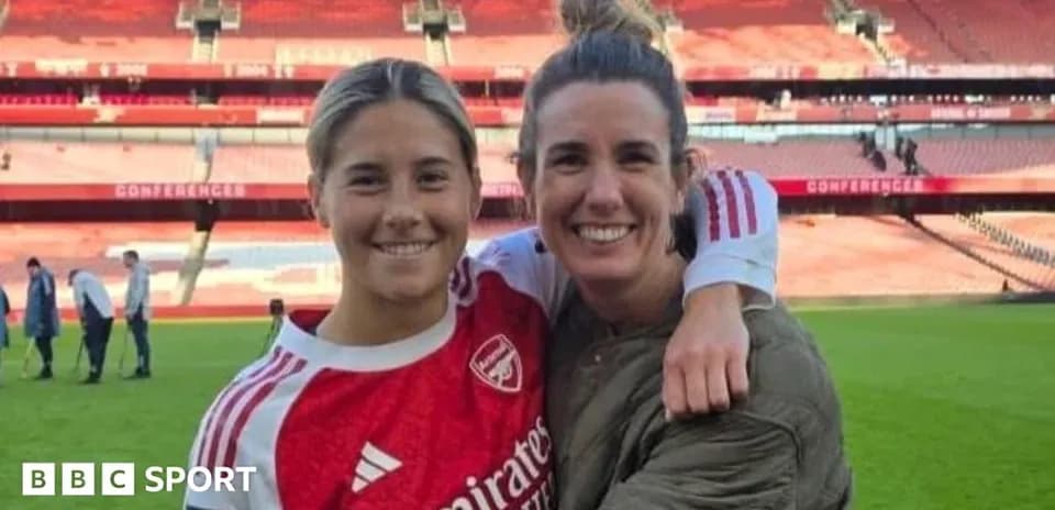 Two women smiling together on football pitch
