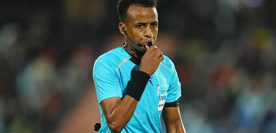Referee holding whistle during football match
