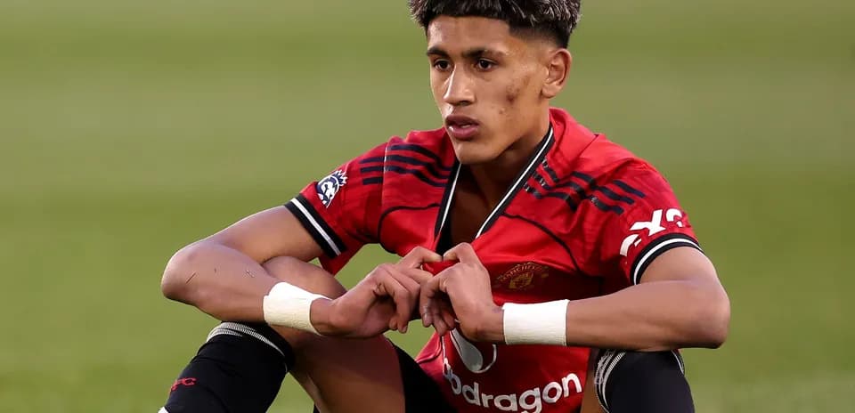Player sitting on field wearing Manchester United kit