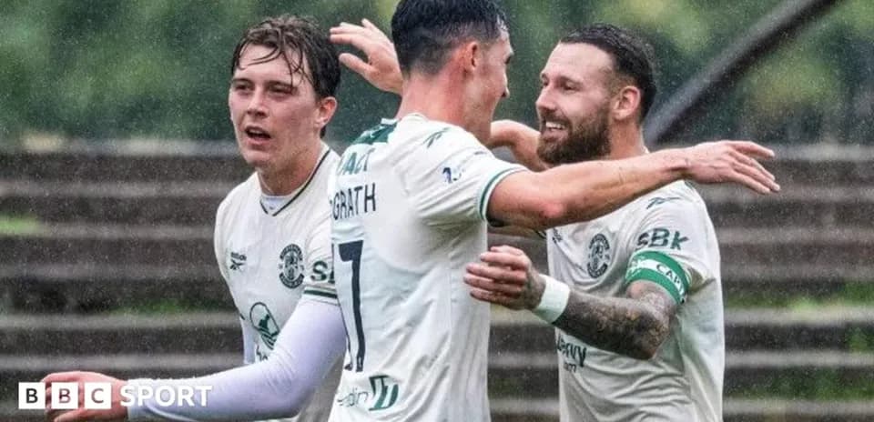Players celebrating a goal in the rain