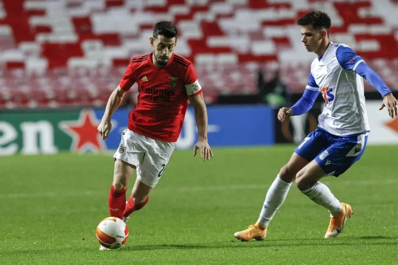 Benfica player dribbling against Lech Poznan opponent
