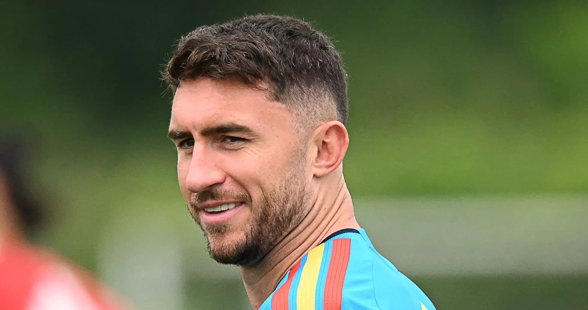 Football player in training kit smiling outdoors