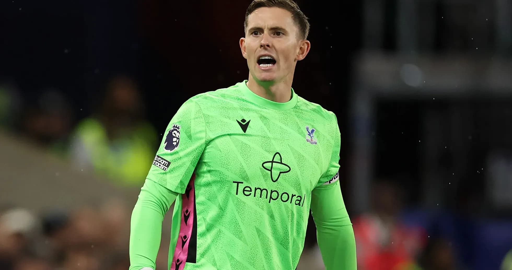 Goalkeeper in green kit shouting during match