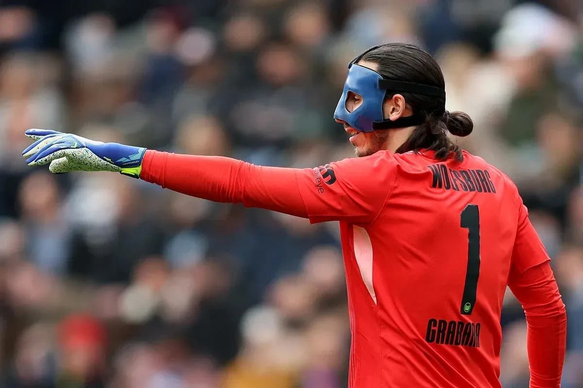 Goalkeeper in red jersey directing play on field