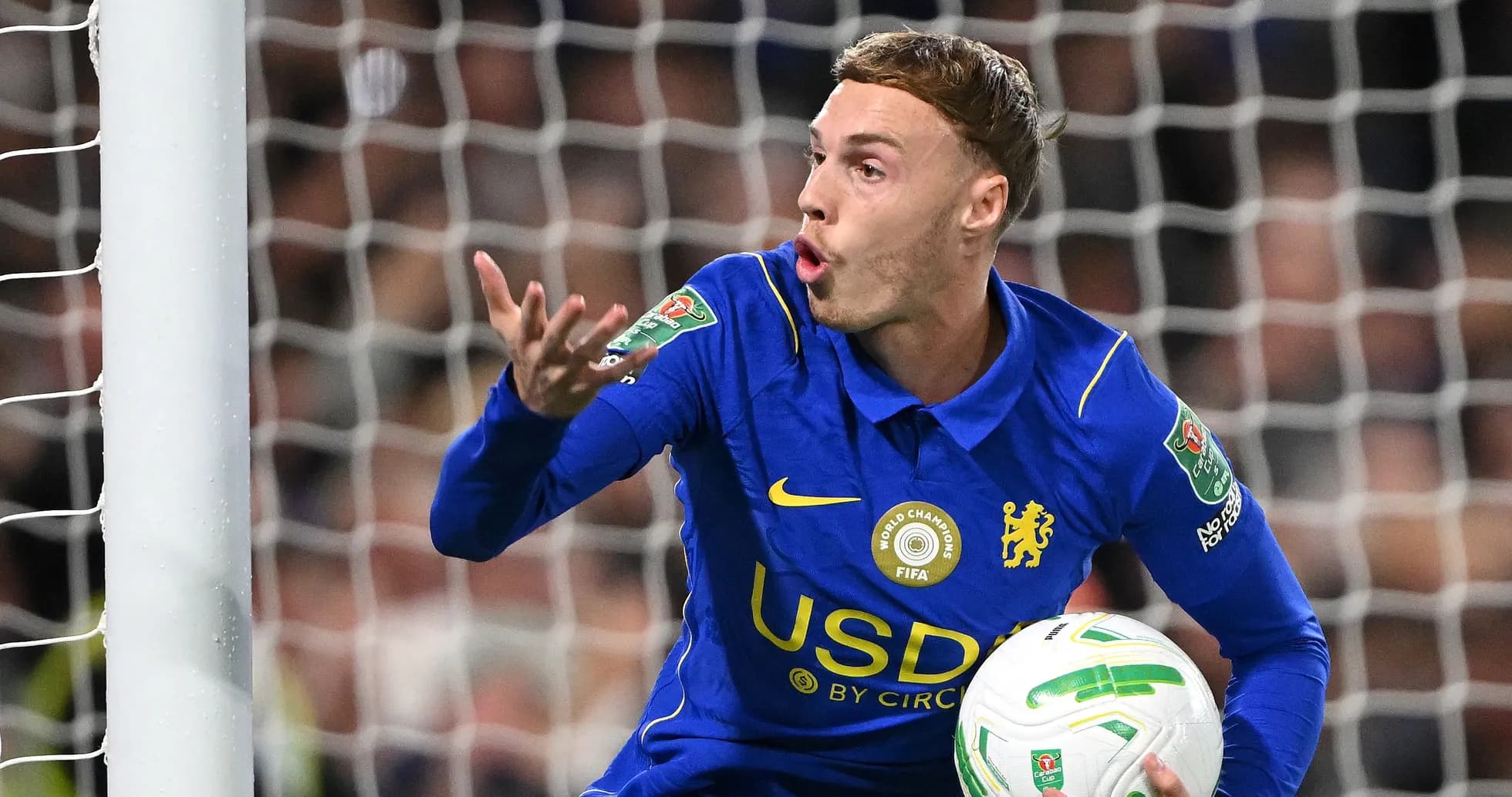 Player gesturing while holding a football in goal