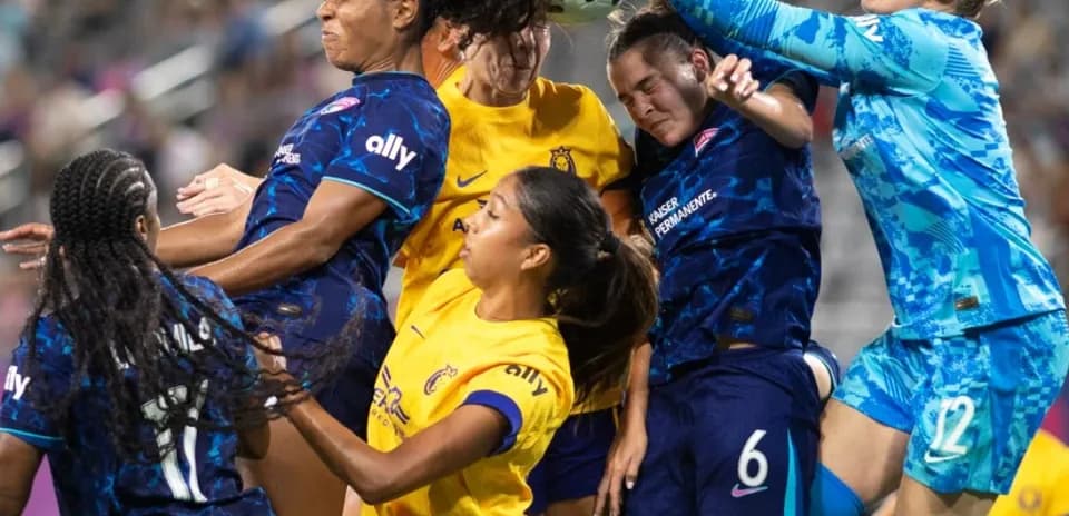 Players contesting a high ball in NWSL match
