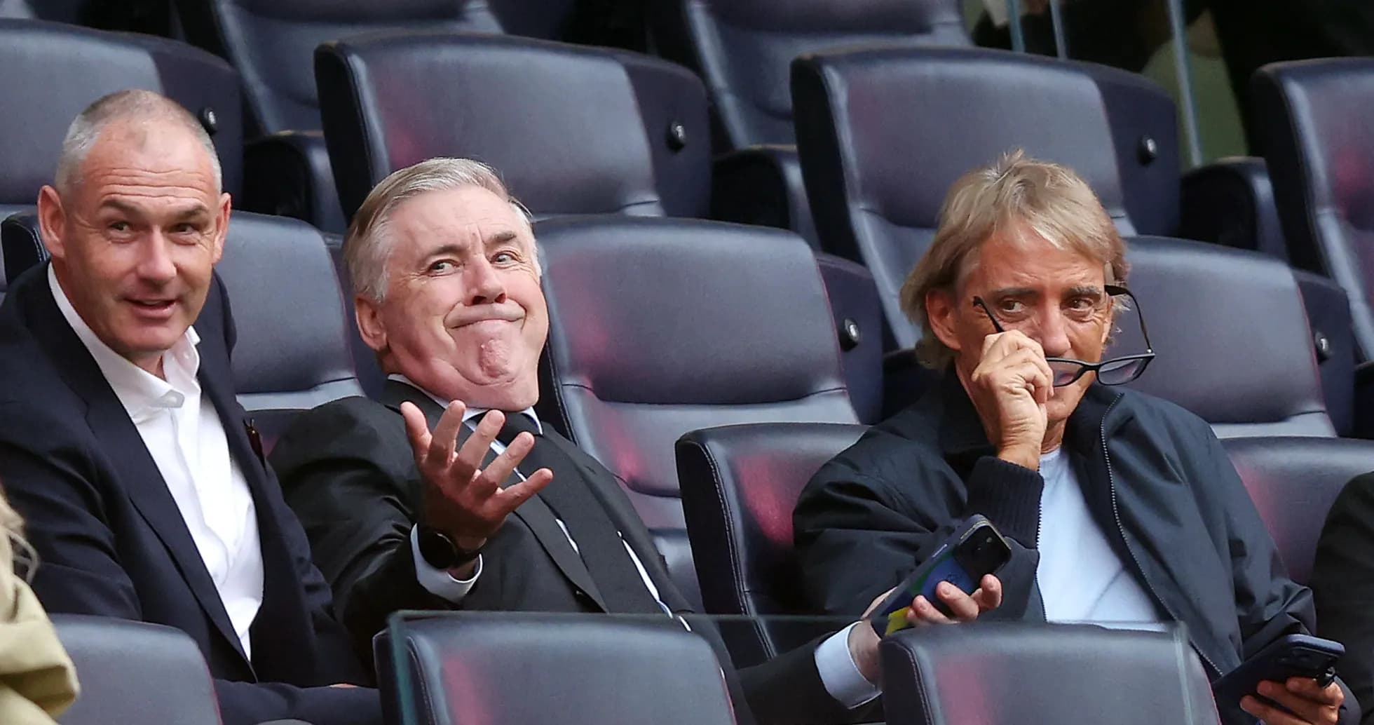 Three men seated in a stadium viewing area