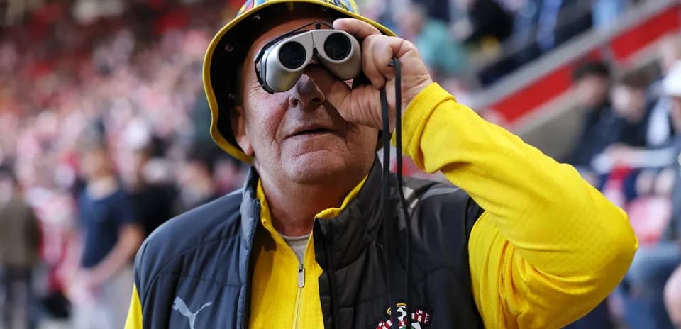 Fan wearing binoculars at a football match
