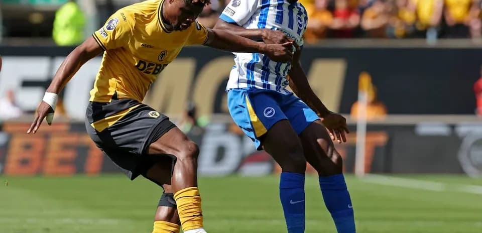 Brighton player challenging Wolves player for ball