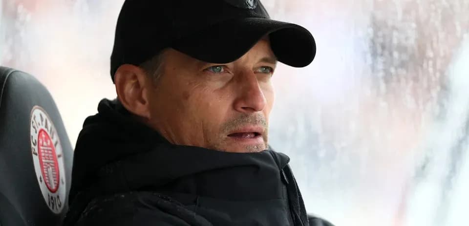 Coach seated on bench during rainy match