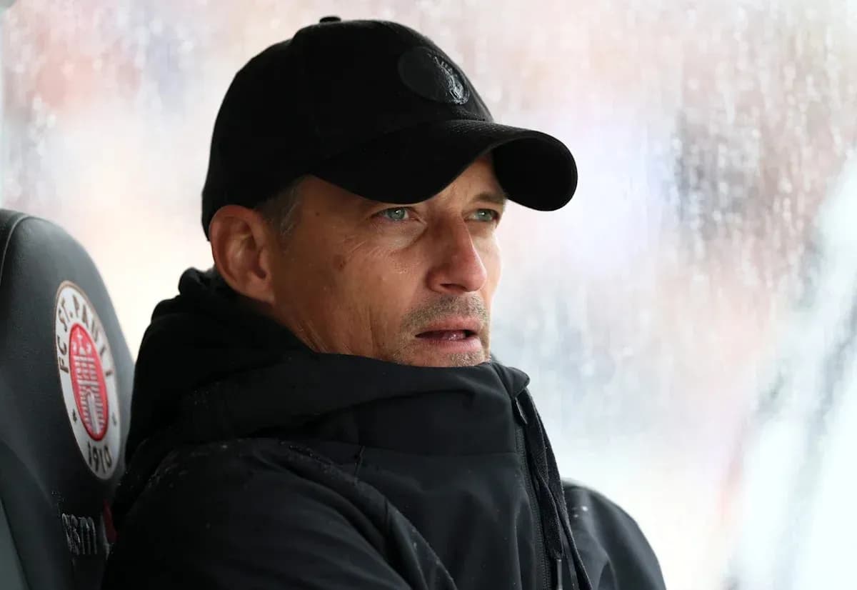 Coach seated on bench during rainy match