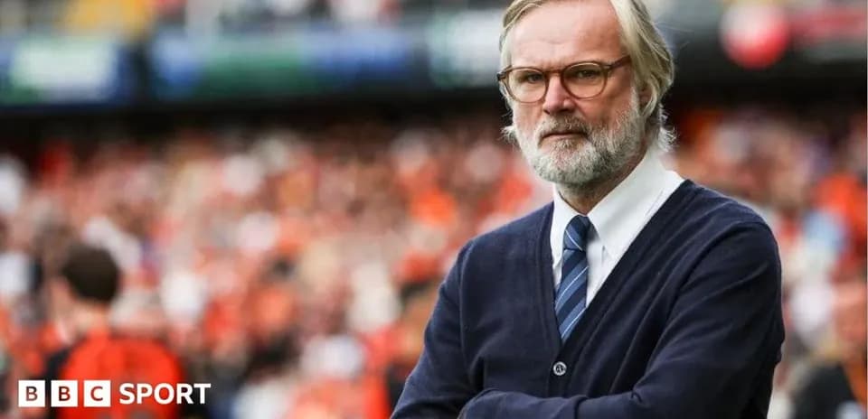 Coach observing match with arms crossed in stadium