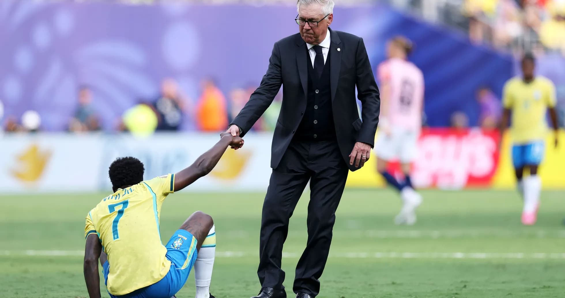 Coach assisting player sitting on the field