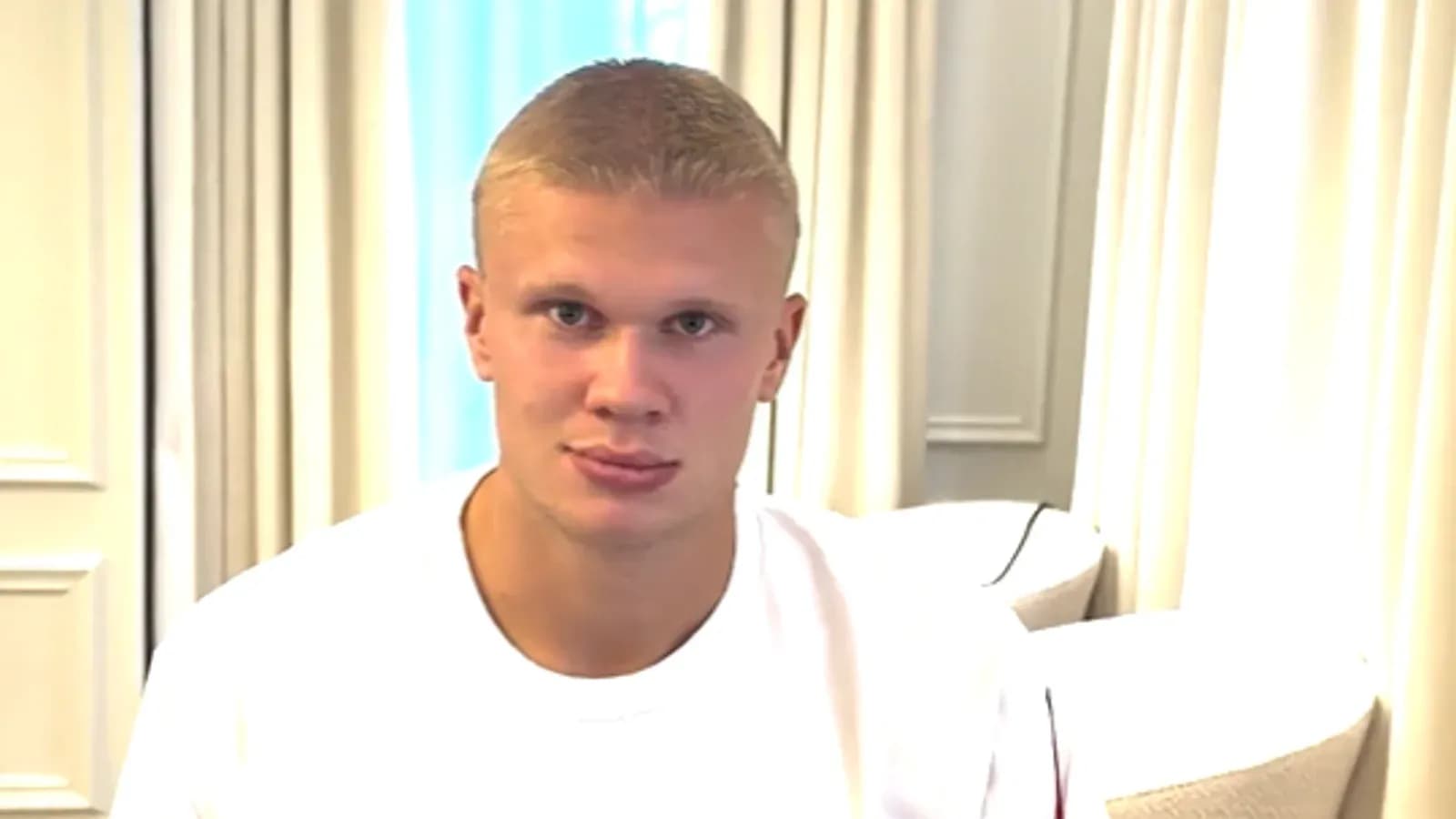 Young man sitting indoors wearing a white shirt