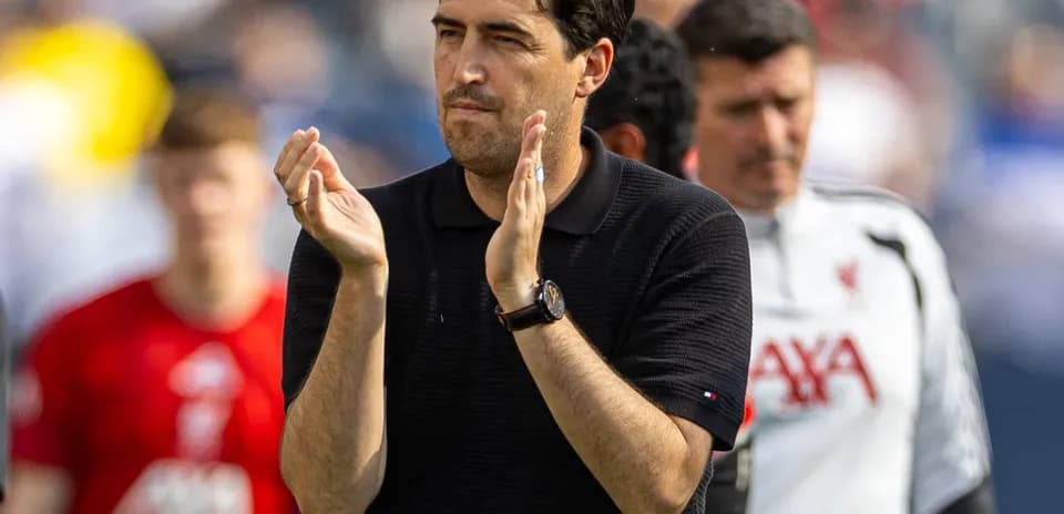 Coach clapping during match with players in background