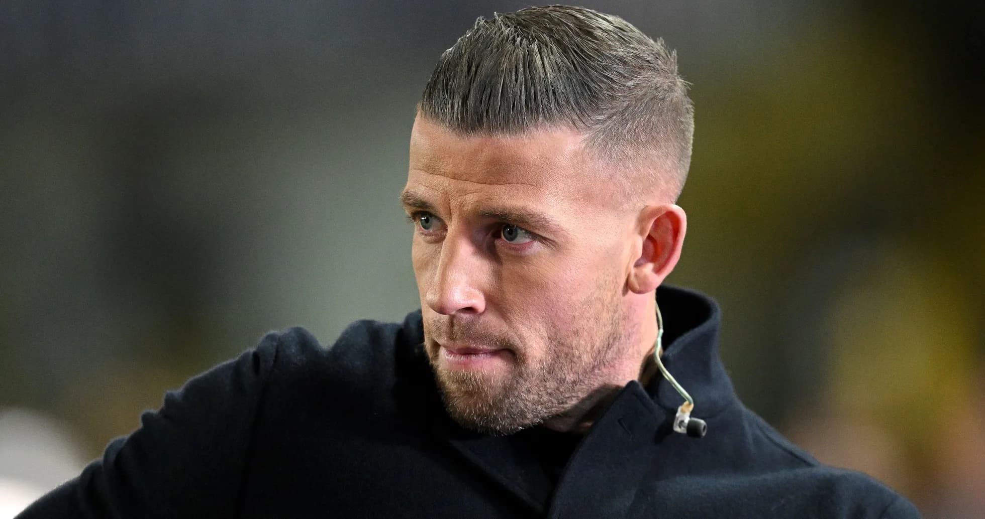Man in dark coat looking intently at event