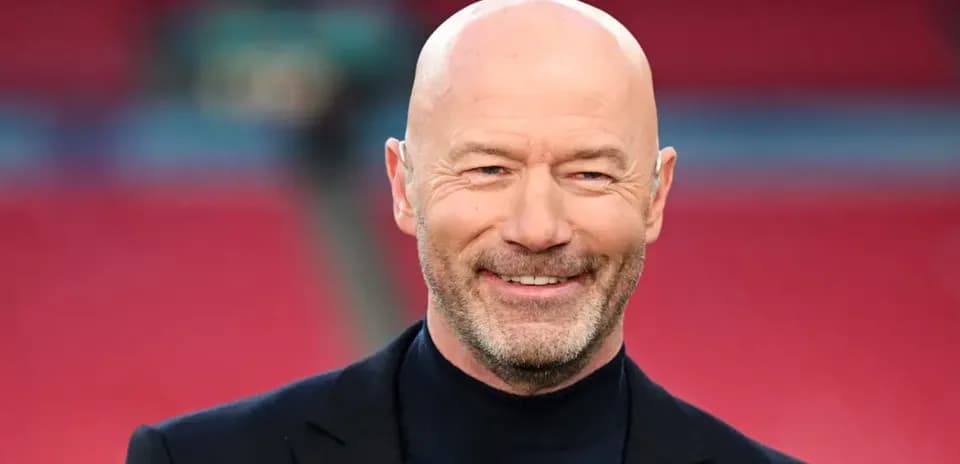Man smiling in a suit at a stadium