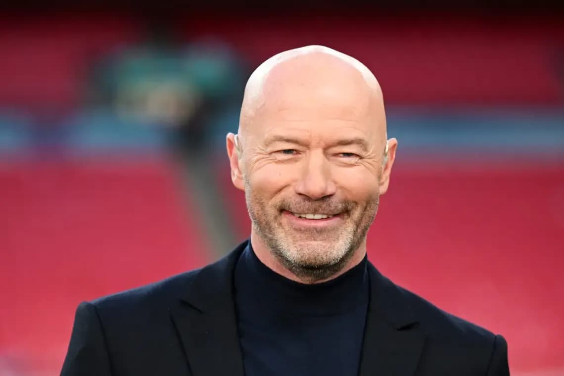 Man smiling in a suit at a stadium