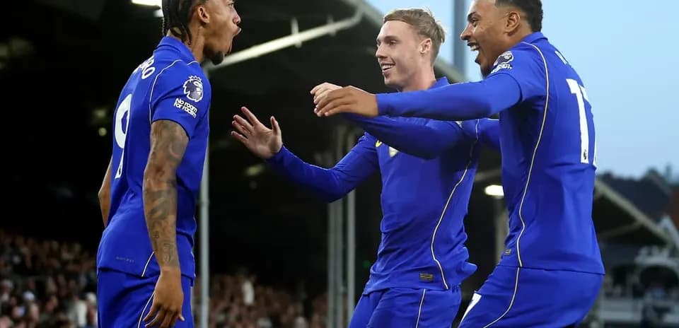 Three players celebrating a goal on the field