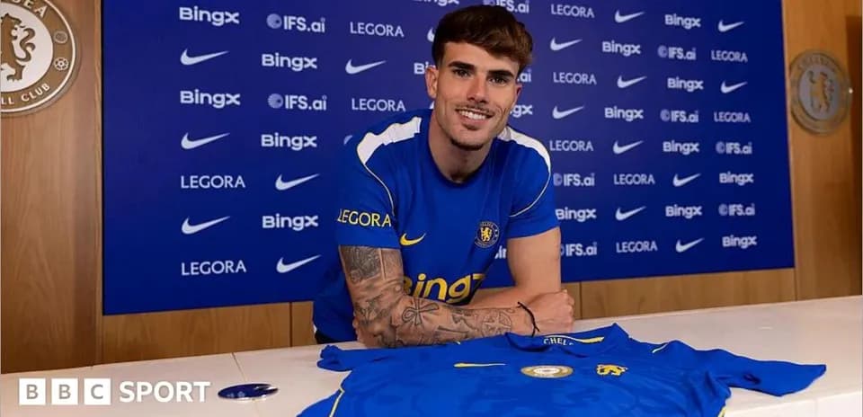 Player posing with Chelsea jersey at press conference