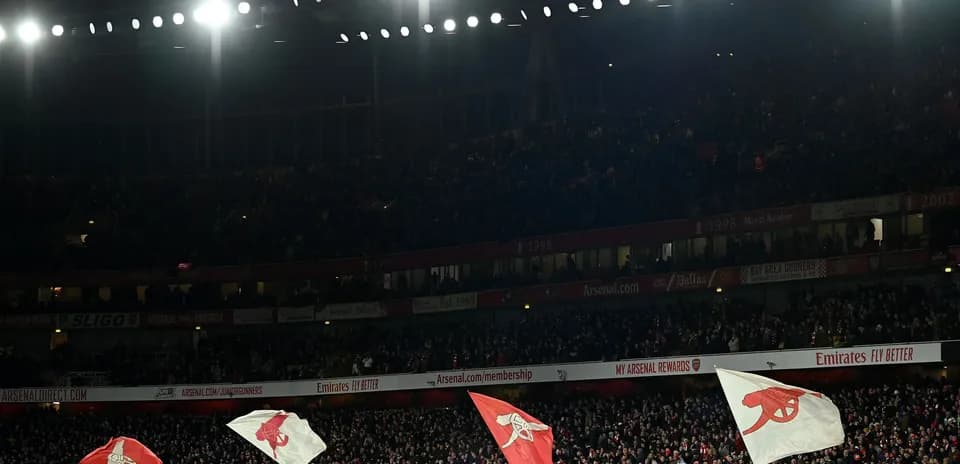 Fans waving Arsenal flags in packed stadium