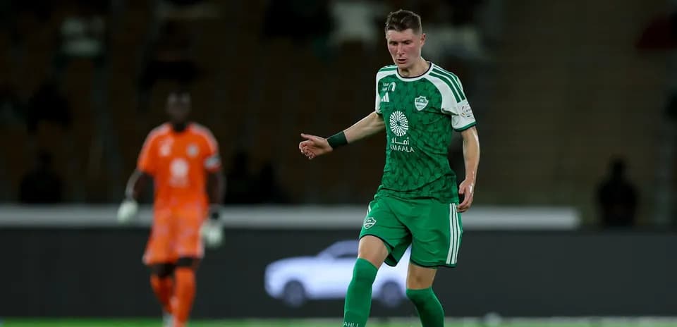Player in green kit dribbling the ball on field