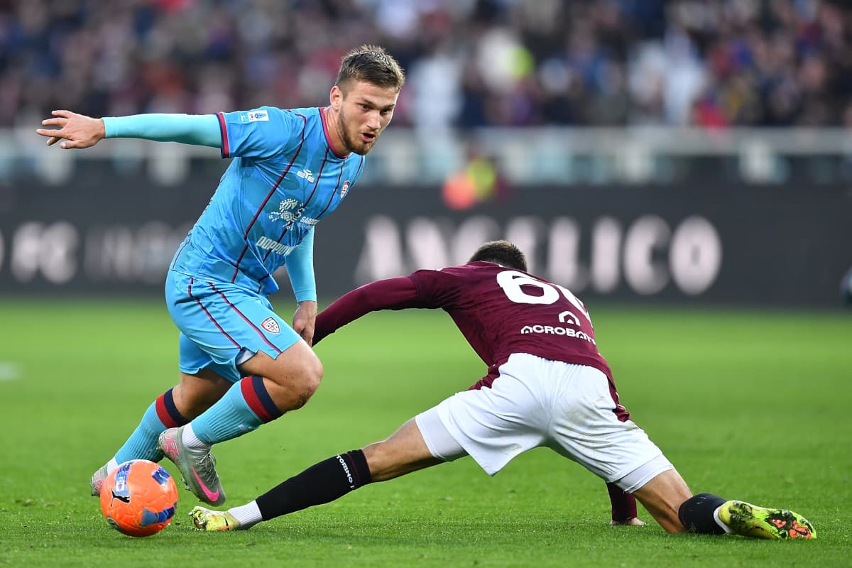 Cagliari player evading Torino tackle during match