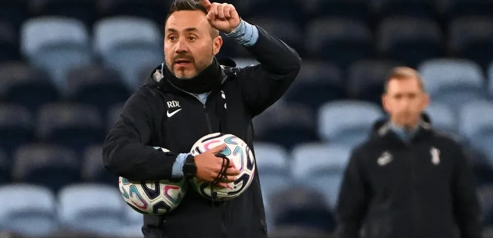 Coach instructing during training session with footballs