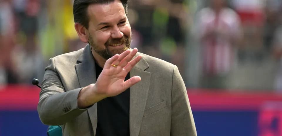 Man in suit waving at the crowd during event