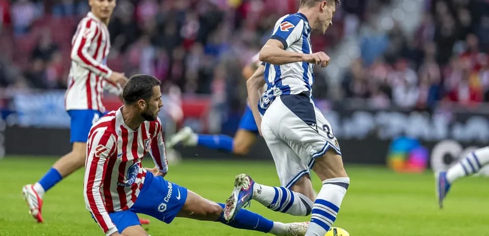 Real Sociedad player evading Atletico Madrid tackle