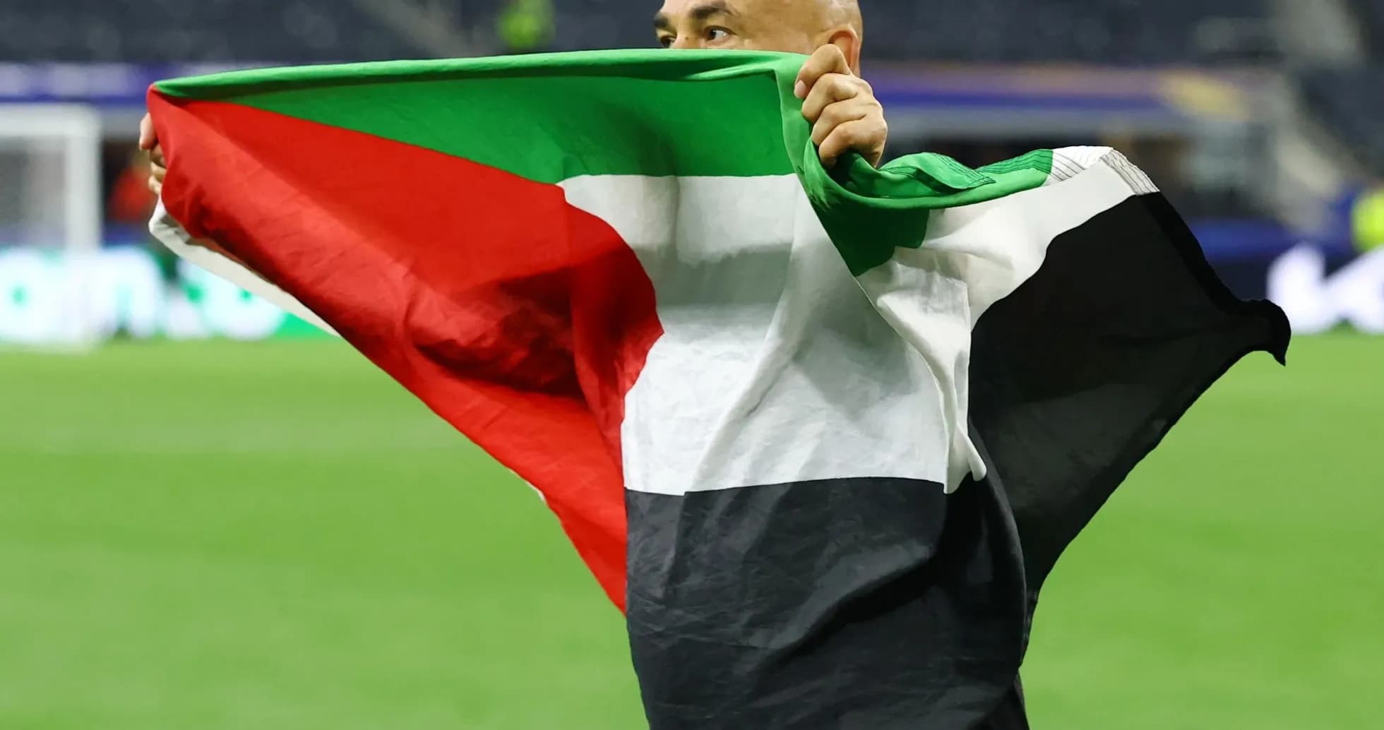 Person holding Palestinian flag on the field