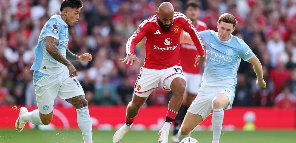 Manchester United player challenged by Manchester City defenders