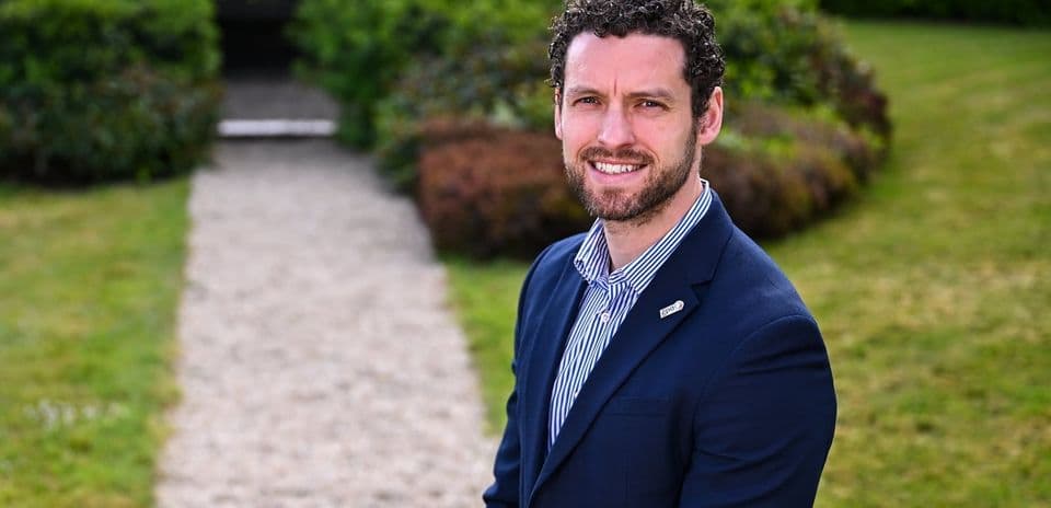 Man in suit standing on gravel path outdoors