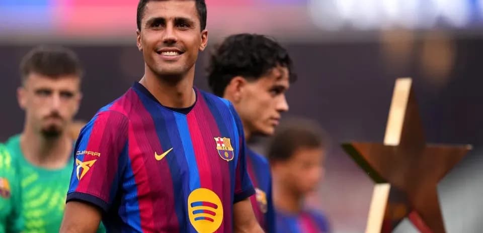 Player smiling while holding trophy on field
