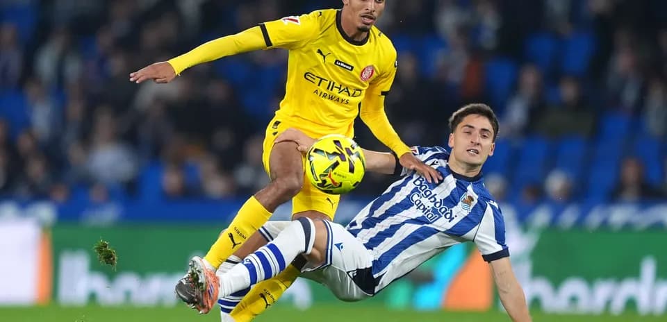 Girona player dribbling against Real Sociedad player