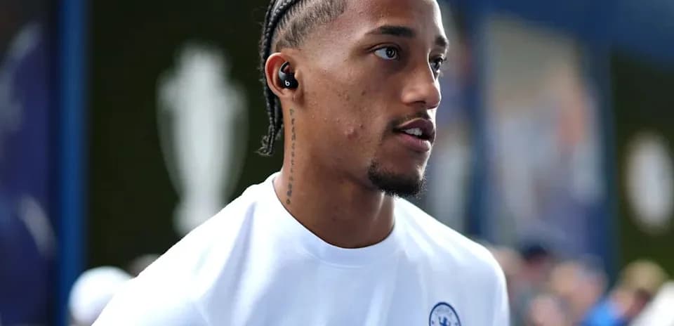 Player wearing Chelsea shirt with earbuds in stadium