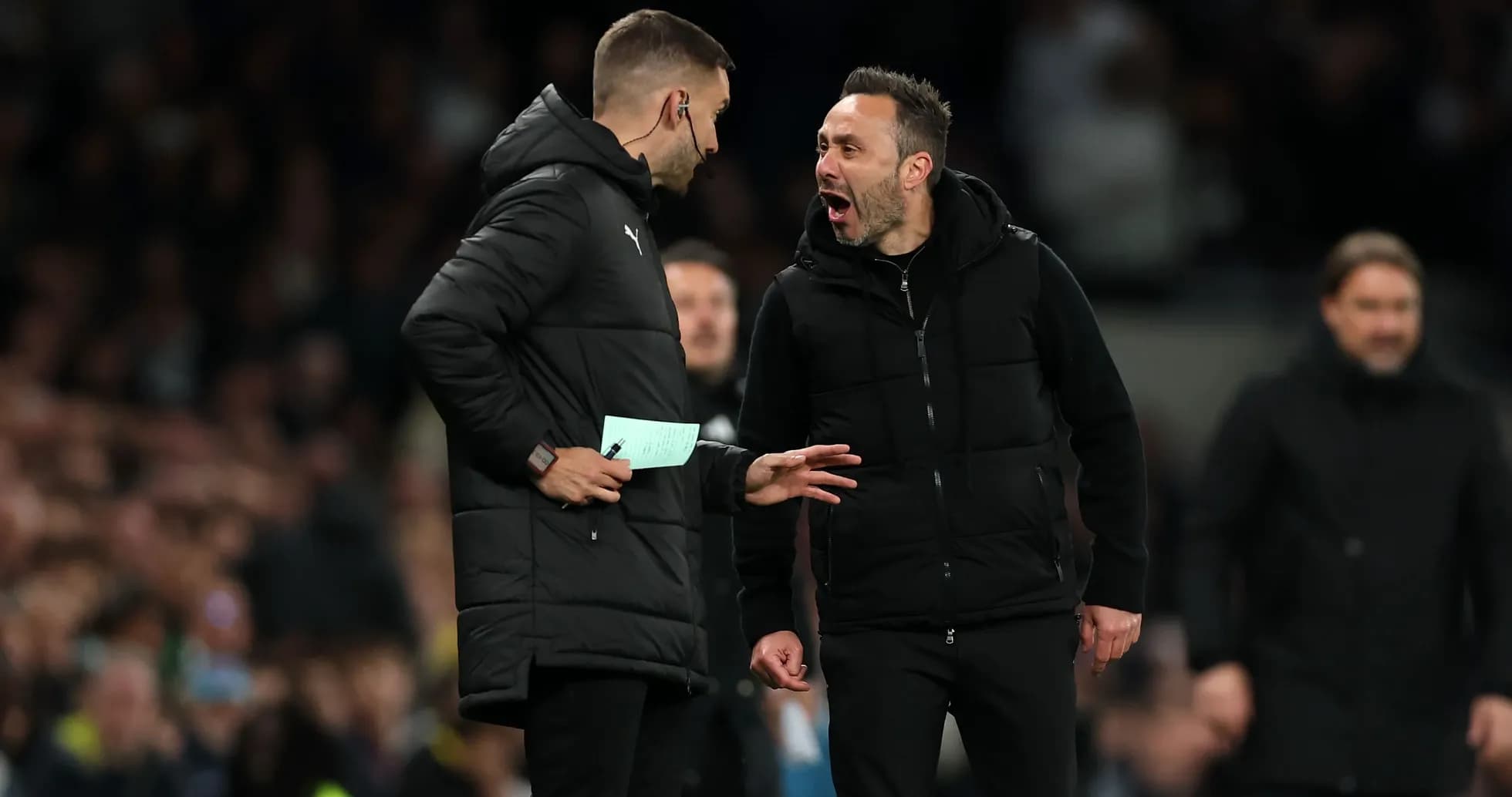 Two coaches discussing animatedly on the sideline