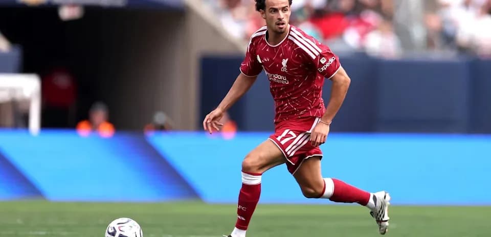 Player in Liverpool kit dribbling ball on field
