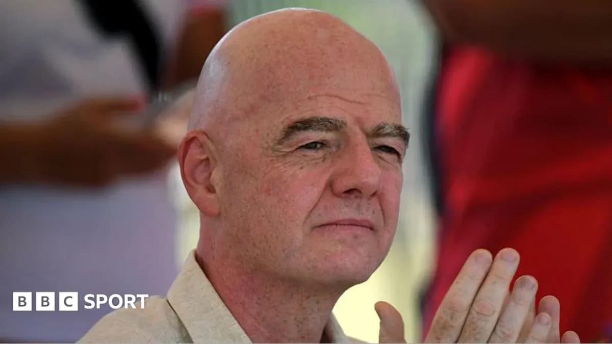 Man with bald head seated, hands clasped together