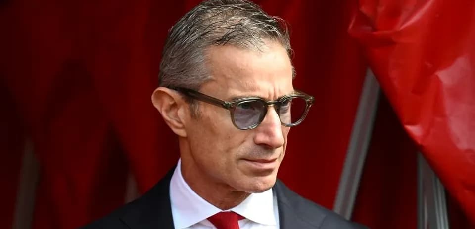 Man in suit and glasses standing by red backdrop