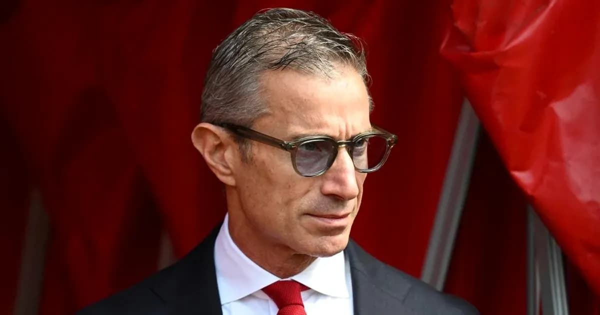 Man in suit and glasses standing by red backdrop