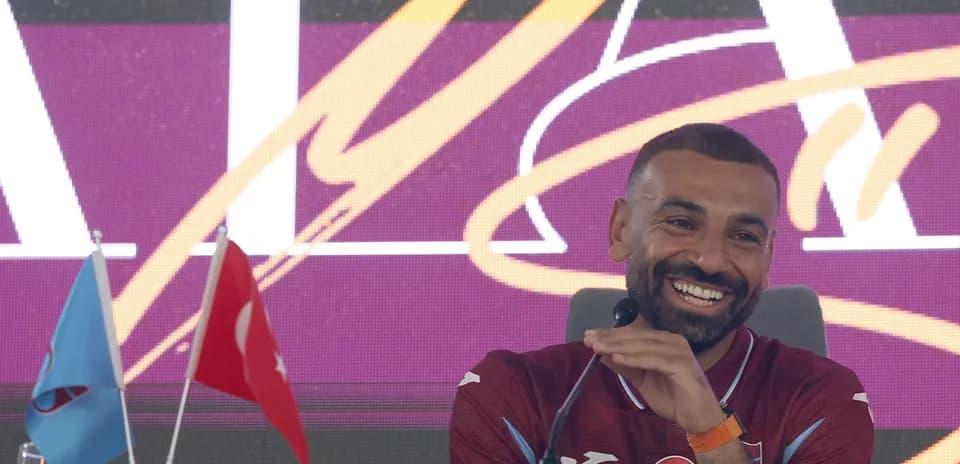 Player speaking at press conference with flags