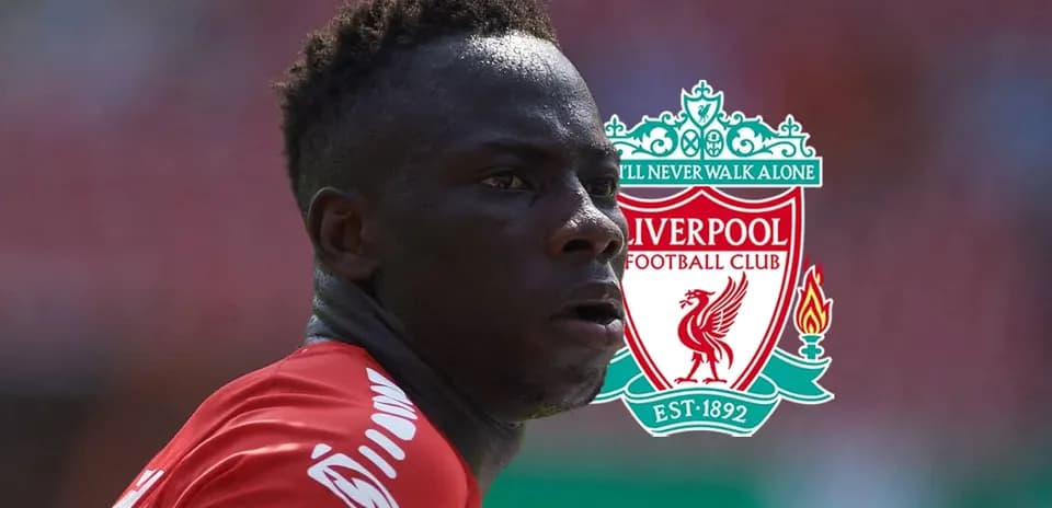 Player in Liverpool kit with club logo in background